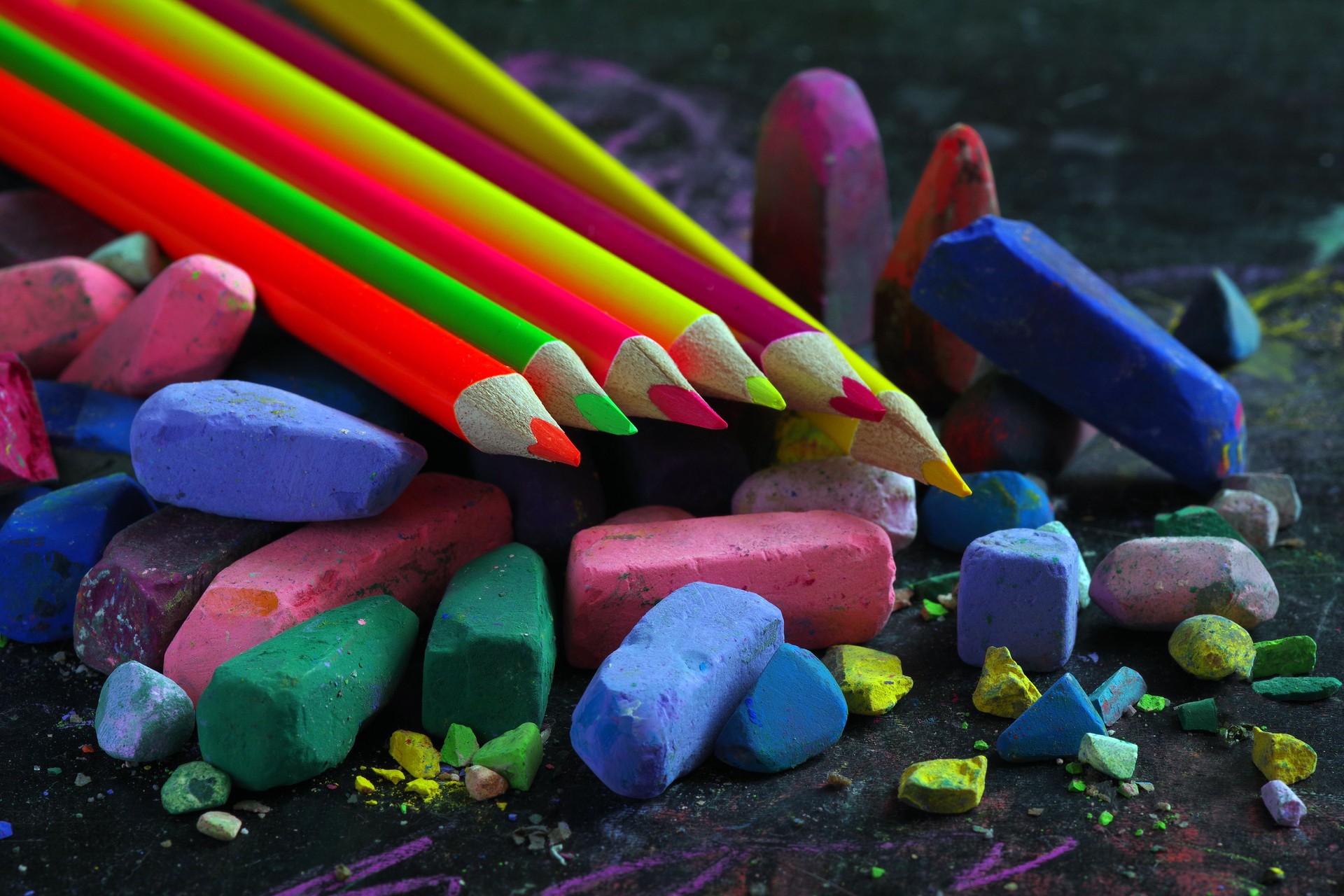 multicolored pastel crayons and colored pencils on black drawing board close up